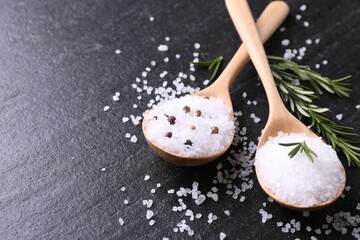 Salt with fresh rosemary and peppercorns on dark grey textured table, closeup. Space for text