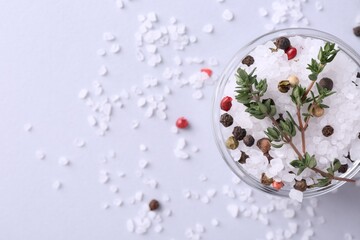Salt with peppercorns and thyme in bowl on light table, top view