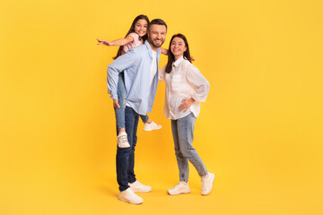 family posing together kid daughter piggybacking and spreading arms, studio