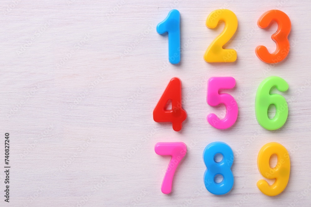 Poster Colorful numbers on white wooden school desk, flat lay. Space for text