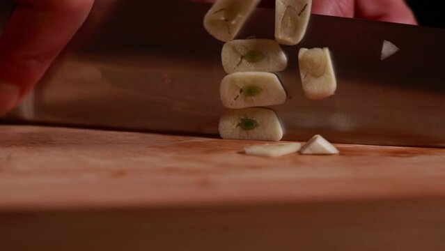  woman hands cutting, chopping, dicing garlic close-up on wooden board