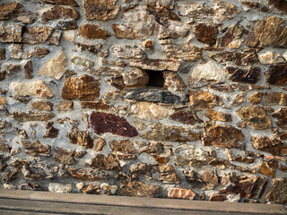 imagen detalle textura pared de piedras de distintos tamaños con las juntas de cemento y un agujero en medio