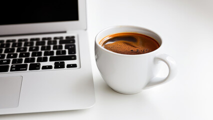 Obraz na płótnie Canvas Simple and clean image of a hot coffee cup next to a modern laptop on a white background, symbolizing remote work and productivity.