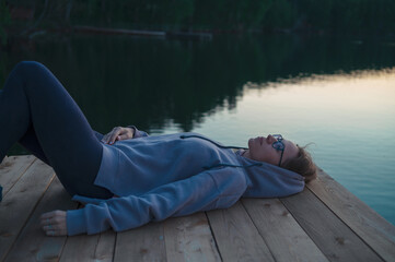 Woman lying down on the pier at lake