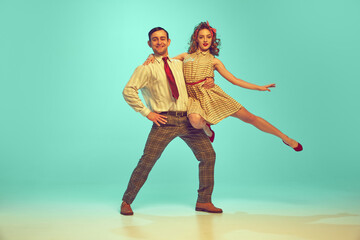 Pretty young couple in retro 80s, 90s fashion style outfit dancing against gradient mint background. Look happy, excited, delighted. Concept of music and art, beauty, energy, happiness, mood, action.