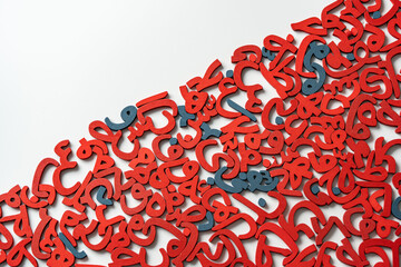 Top View image of a group of Arabic letters made of wood, colored red and blue on a white background