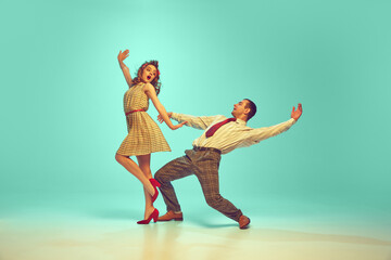Two dancers, man and woman dressed retro outfits in mid-twirl, embodying 50s swing dance enthusiasm...