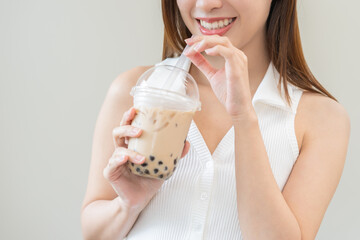 Beverage and food concept, Happy asian young woman hand holding plastic cup, glass of drink bubble, pearl milk tea with straw, cute girl drinking ice cold tea with tapioca boba ball popular in Taiwan.