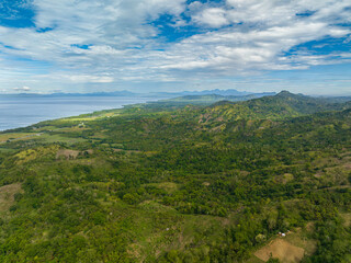Aerial view of Mountains covered rainforest, trees and blue sky with clouds. Mindanao, Philippines.