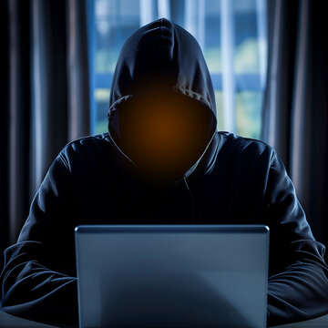 Hacker stealing data from laptop. Dark face. Blurred background.