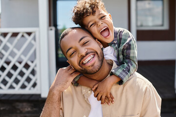positive african american boy hugging excited father in braces on backyard of house, quality time © LIGHTFIELD STUDIOS