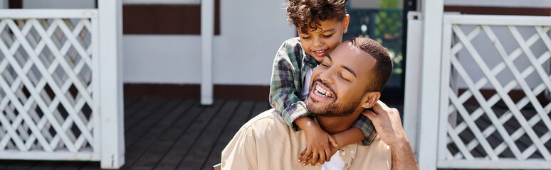Fototapeta premium positive african american kid hugging father while having bbq on backyard of house, banner