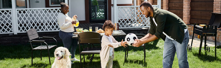 family weekend banner, happy african american father giving soccer ball to son on backyard of house - 740867278