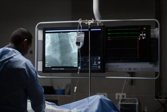 doctor with patient. Preparing a patient for surgery against the backdrop of a large monitor. cardiovascular surgery. Coronary angiography of the heart vessels