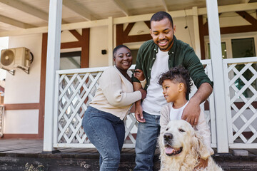 family photo, happy african american parents and son playing with dog on backyard of their house