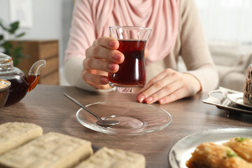 Woman with cup of delicious Turkish tea at wooden table, closeup