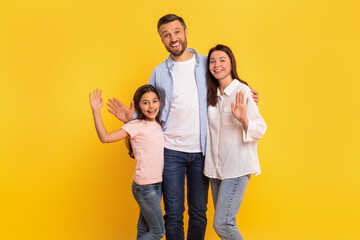 Fototapeta premium Cheerful family of parents and daughter kid waving hands, studio