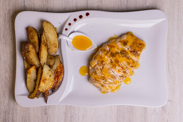 Petto di pollo cotto a bassa temperatura e poi finito sulla brace servito con salsa agrodolce e contorno di patate al forno in una braceria