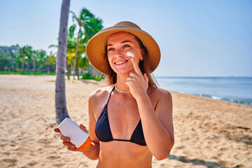 Portrait of satisfied young joyful happy smiling woman using facial spf sunscreen while sunbathing and relaxing in the sun. Sunburn protection and healthy skin