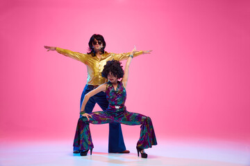 Retro dance styles. Attractive young couple, man and woman performing disco against gradient pink...
