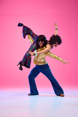 To rhythm of dance. Talented couple, dance partners in dynamic disco pose against gradient pink...