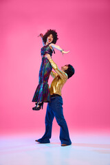 To rhythm of dance. Talented couple, dance partners in dynamic disco pose against gradient pink...