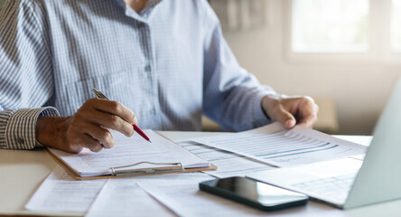 Asian businessman reviewing document reports at office workplace with computer laptop. legal...