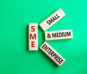 SME - Small and Medium Enterprise symbol. Wooden cubes with words SME. Beautiful green background. Business and SME concept. Copy space.
