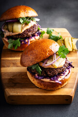 Beef burgers with pickles and red onion on cutting board - 740877456