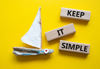 Keep it Simple symbol. Concept words Keep it Simple on wooden blocks. Beautiful yellow background...