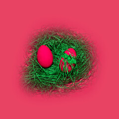 Easter eggs in a nest of grass on a pink background.