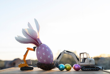 two small models of toy excavators, an eggshell with a large magnolia flower, multi-colored...