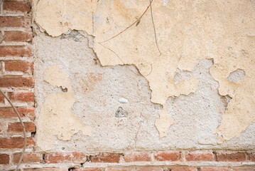 Wall of a light-colored ruined house with exposed bricks