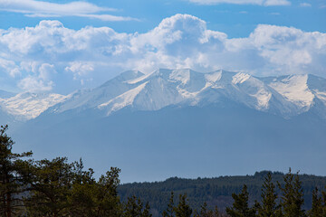 Snowy mountain peak and cloudy sky in February. Nature background, global warming, care for the planet.