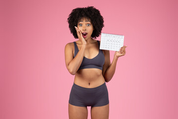Surprised black woman holding personal tracking calendar