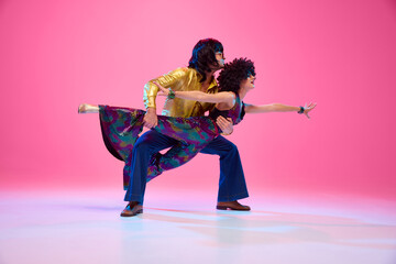 Full length portrait of talented people, dancers duo energetically moves against gradient pink...