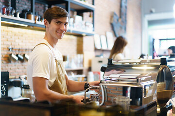 Professional young coffee barista standing inside the counter bar in the coffee shop and making...