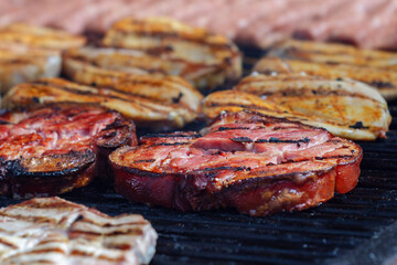Roasted pork knuckle, chicken breast, and traditional Romanian mititei on the grill, from close-up, focus on pork knuckle