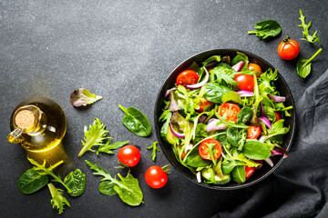 Salad in black bowl at dark background.