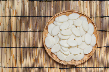 slice Tteok or slice Korean rice cake in bowl on bamboo table food background. flat lay overhead