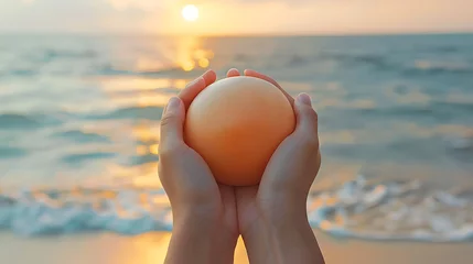 Zelfklevend Fotobehang Hands Cradling an Orange Sphere at Sunset Beach © tongpanyaluk