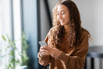 teen girl leisurely using cell phone for texting at home