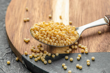 fregola pasta on spoon on wooden background top view. copy space