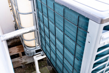 Outdoor unit of a low-power air heat pump located in front of the house.