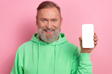 Photo of funky positive guy dressed green hoodie showing apple iphone samsung device empty space...