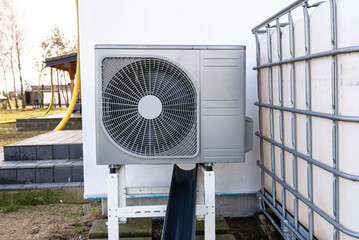 Outdoor unit of a low-power air heat pump located in front of the house.