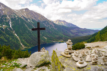 christian cross above the Morskie Oko mountain lake and hiking destination  - obrazy, fototapety, plakaty