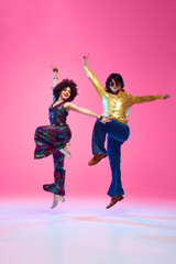 Talented dancers, man and woman in retro style outfits posing against gradient pink studio background. Concept of American culture, 1970s, 1980s fashion, music, comparisons of eras.