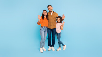Happy family of three waving hands embracing over blue background