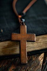 Closeup of wooden Christian cross necklace next to holy Bible - obrazy, fototapety, plakaty